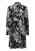 Schwarzes Hemdkleid mit weißem Blumenmuster. Lange Ärmel, Kragen, geraffte Taille und eine fließende Silhouette. Weiche Stoffstruktur.