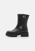 Schwarze Leder-Ankle-Boots mit einer klobigen Sohle, ausgestattet mit zwei Riemen mit silbernen Schnallen. Glatte Oberfläche und robuste Textur an der Sohle.