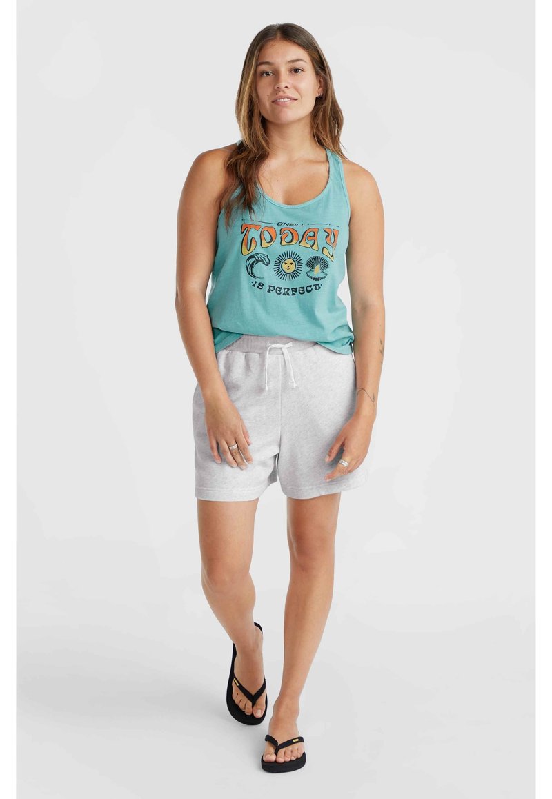 Türkises Tanktop mit grafischem Text, kombiniert mit hellgrauen Shorts mit Kordelzug. Model trägt schwarze Flip-Flops und steht vor einem neutralen Hintergrund.