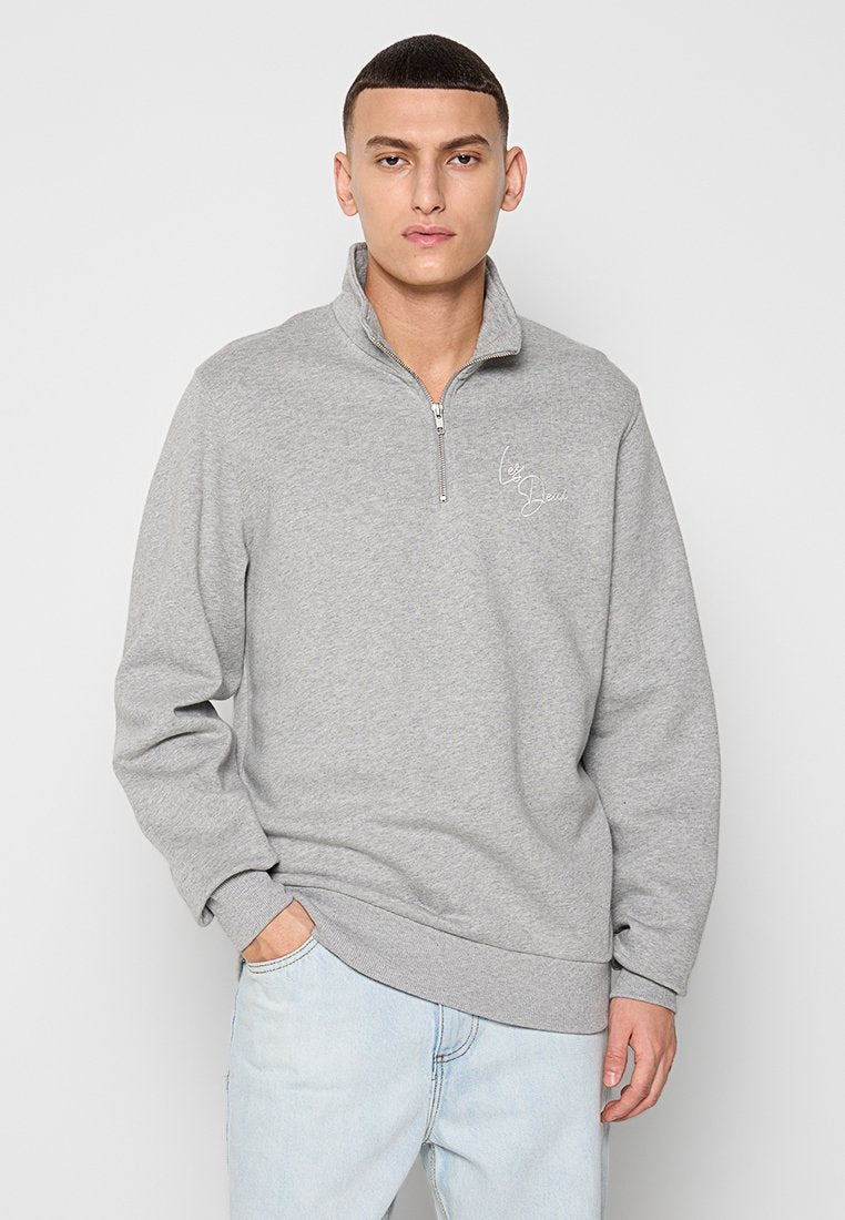 Hellgrauer Sweatshirt mit einem halben Reißverschlusskragen, aus weichem, strukturiertem Material. Verfügt über ein gesticktes Design auf der Brust.