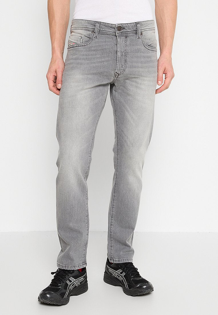 Herren graue Denim-Jeans mit geradem Schnitt, klassischem Five-Pocket-Design, dezentem Verblassen und robuster Naht. Getragen mit schwarzen Sneakers.