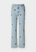 Hellblaue Jeans aus Denim mit geraden Beinen, versehen mit kleinen, bestickten roten und goldenen Wappenaufnähern, die über den Stoff verteilt sind.