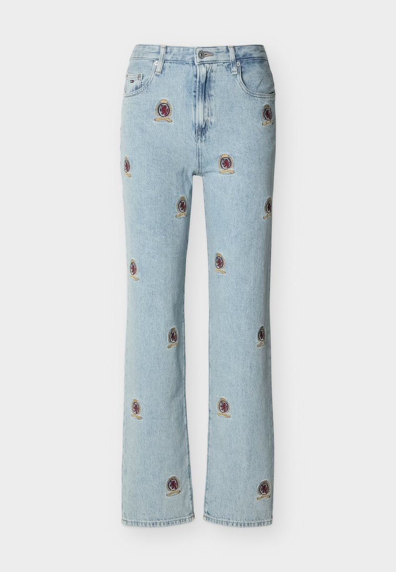 Hellblaue Jeans aus Denim mit geraden Beinen, versehen mit kleinen, bestickten roten und goldenen Wappenaufnähern, die über den Stoff verteilt sind.