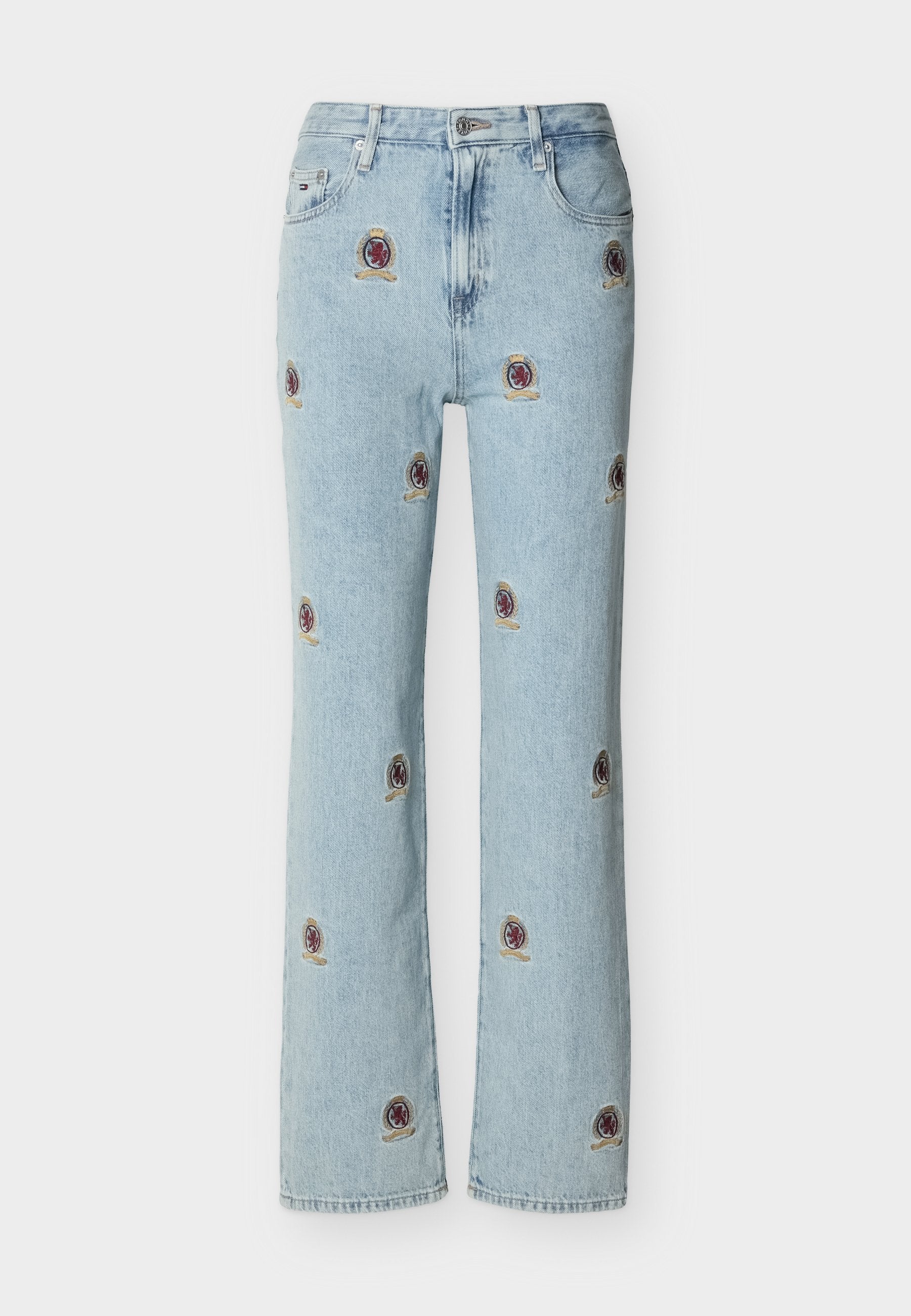 Hellblaue Jeans aus Denim mit geraden Beinen, versehen mit kleinen, bestickten roten und goldenen Wappenaufnähern, die über den Stoff verteilt sind.