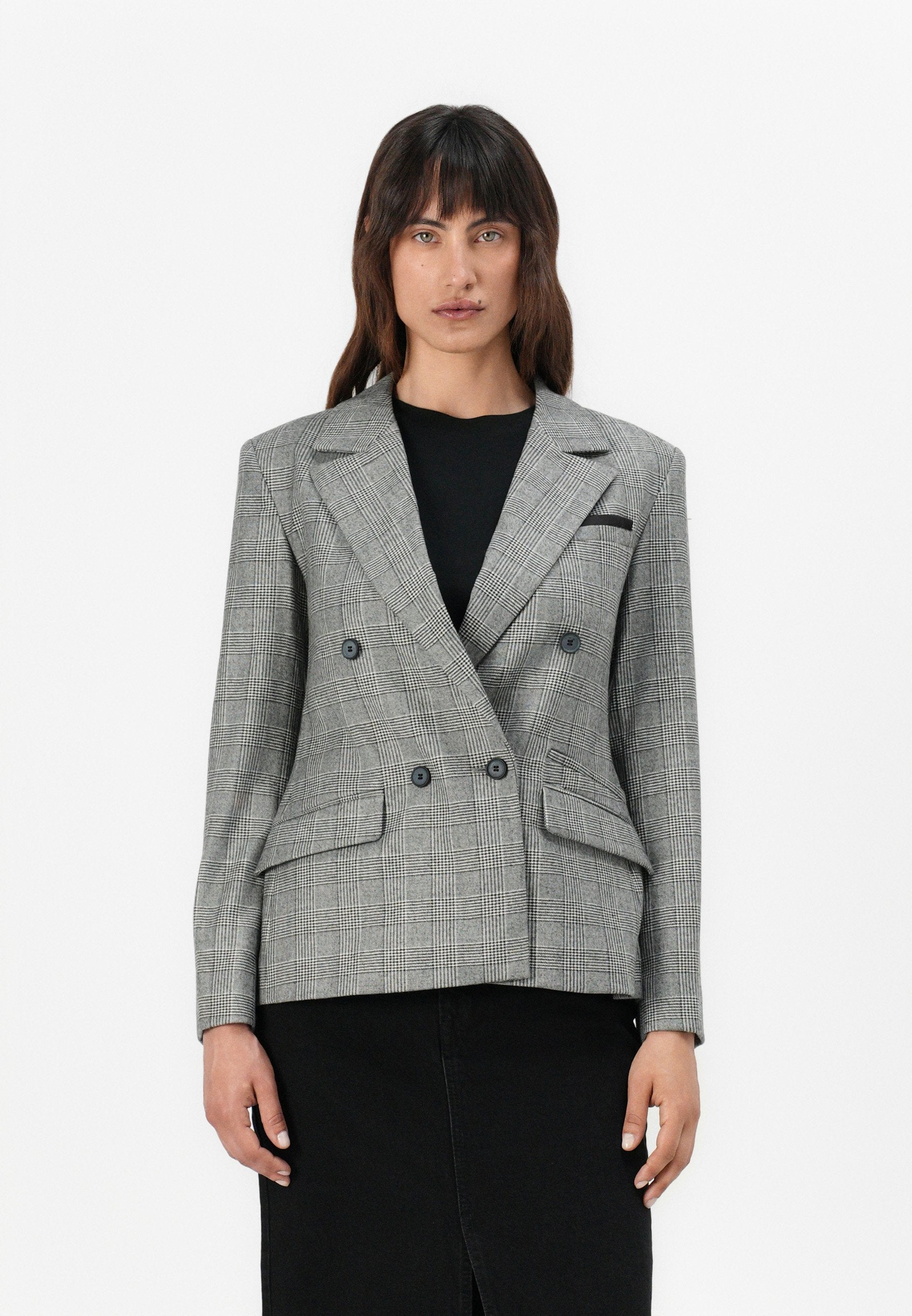 Doppelt gefütterter Blazer im grauen Hahnentpattern, mit Spitzenlapels, zwei Fronttaschen und Knopfakzenten, kombiniert mit einem schwarzen Oberteil.