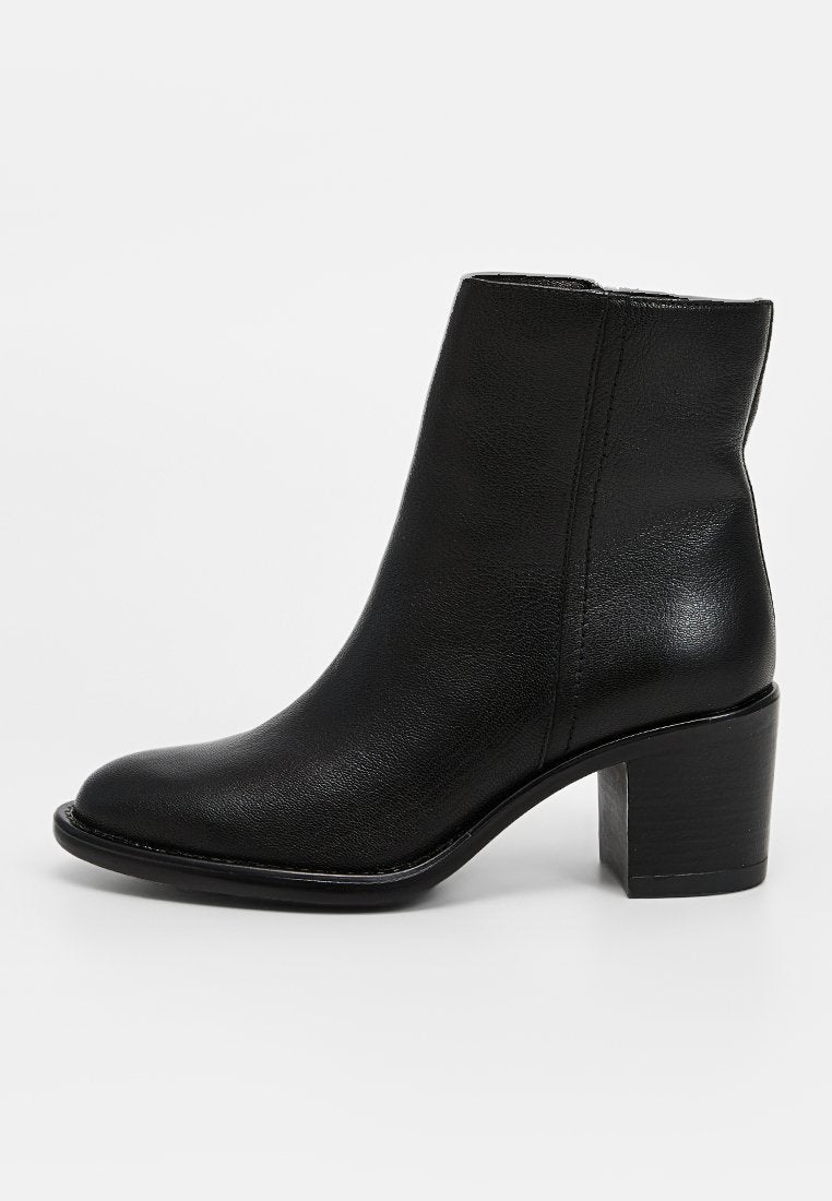 Schwarze Leder-Stiefel mit rundem Zehenbereich, glatter Textur und klobigem Blockabsatz. Nahtdetails an den Seiten sorgen für visuelles Interesse.