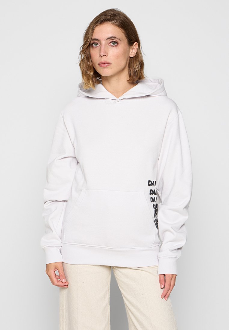 Weiße Kapuzenjacke mit einer Fronttasche und schwarzem Text auf dem Ärmel. Hergestellt aus weichem Material, mit lockerer Passform und verstellbarem Kordelzug an der Kapuze.