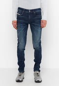 Dunkelblaue Jeans mit schlanker Passform, die leichte Verblassung und subtile Stickdetails aufweisen. Kombiniert mit grauen Sportschuhen.