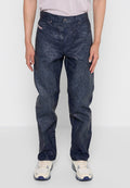 Dunkelblaue Denim-Hosen mit einer geriffelten Textur, ausgestattet mit einem klassischen Fünf-Taschen-Design und einem Knopfverschluss. Getragen mit hellen Schuhen.