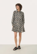 Leopardenmuster-Kleid mit langen Ärmeln und Kragen, mit einem ausgestellt geschnittenen Saum und seitlichen Taschen; kombiniert mit schwarzen Riemchenschuhen.