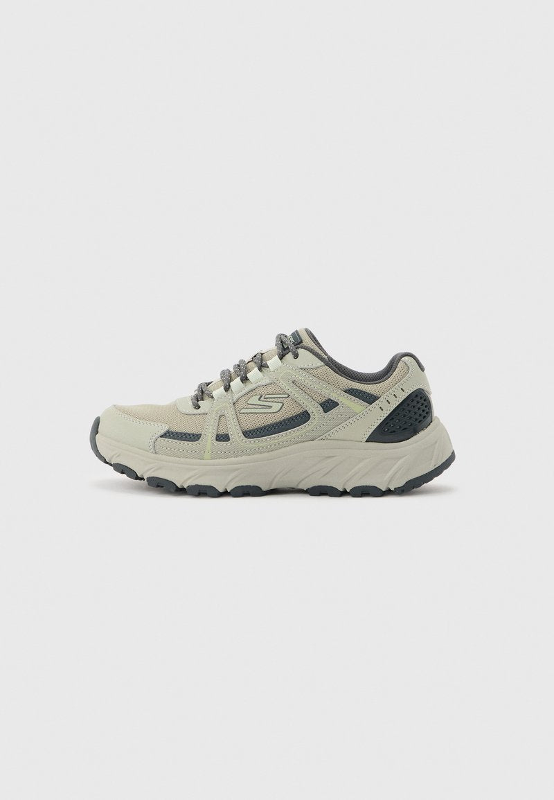 Beiger und grauer Sportschuh mit Mesh- und Synthetik-Obermaterial, dicker gepolsterter Sohle und Schnürverschluss auf einem schlichten hellen Hintergrund.