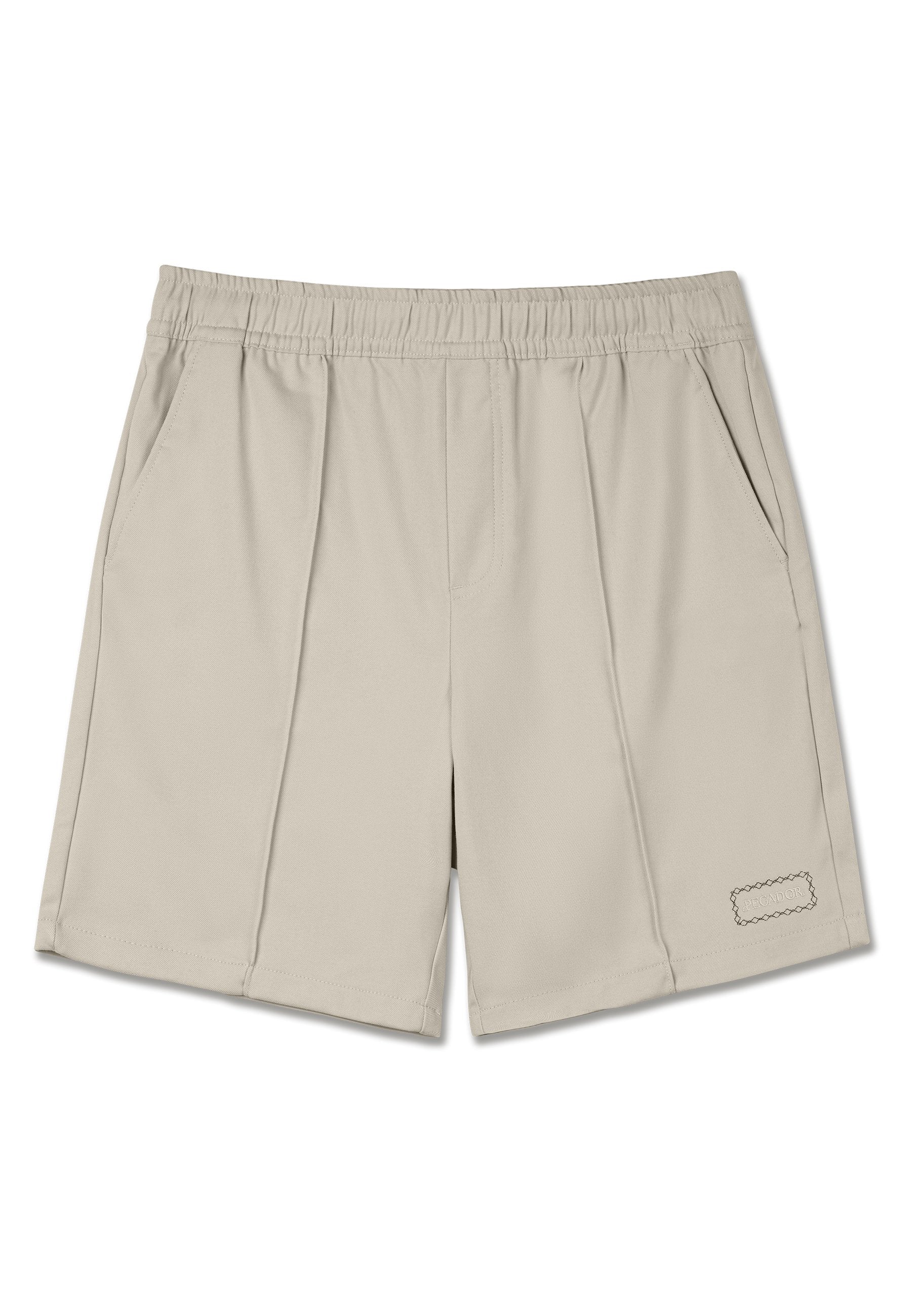 Beige Sportshorts aus weichem Material. Mit einem elastischen Bund, zwei Seitentaschen und einem dekorativen gestickten Etikett am Saum.