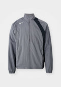 Graue leichte Jacke aus strukturiertem Material, mit hohem Kragen, Reißverschluss und schwarzen Akzenten auf einer Seite. Nike-Logo sichtbar.