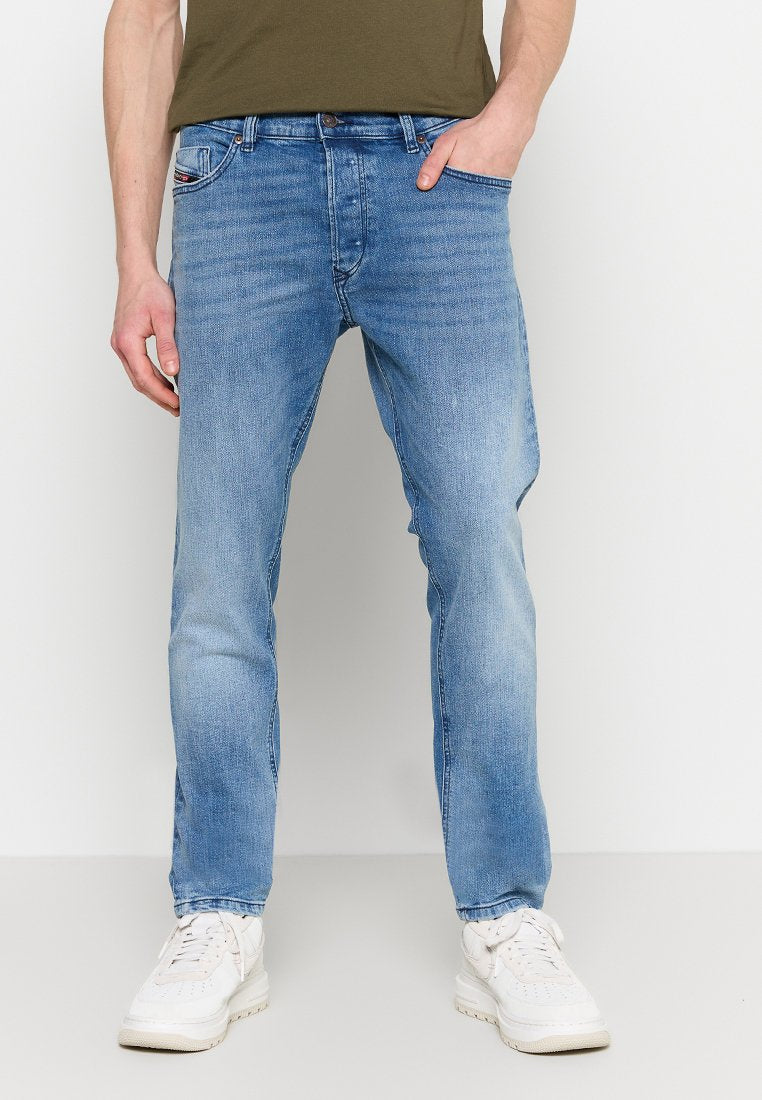 Helles, blaues Denim-Jeans mit geradem Schnitt, ausgestattet mit fünf Taschen und einer dezenten, ausgewaschenen Textur. Kombiniert mit weißen Sneakern.