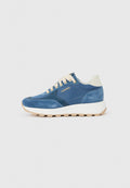 Blauer Wildleder- und Stoffsneaker mit beige Schnürsenkeln, weißem gepolstertem Kragen, klobiger weißer Sohle und dem "AIGNER"-Logo in Gold an der Seite.