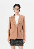 Pfirsichfarbener Blazer mit tailliertem Design, Reverskragen, zwei Fronttaschen und einem goldenen Knopf. Getragen über einem weißen Oberteil und einem schwarzen strukturierten Rock.