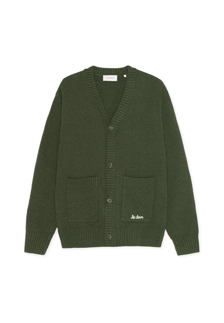 Dunkelgrüner Cardigan mit V-Ausschnitt, gerippten Bündchen und Saum. Zwei Fronttaschen; eine mit weißen, gestickten Text. Fünf Knopfverschluss.