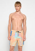 Junger Mann mit kurzem, blondem Haar, der pastellfarbene, batikfarbene Badeshorts mit blauen Seitenpanelen und einem schwarzen Kordelzug trägt.