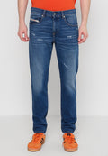 Blaue Denim-Jeans mit geradem Schnitt, die über abgenutzte Details und vier Taschen verfügen. Kombiniert mit orangefarbenen Sneakers und einem Kurzarmhemd.