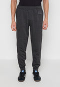 Mann trägt dunkelgraue Jogginghose mit elastischen Bündchen und GAP-Logo an der Hüfte, kombiniert mit schwarzen und weißen Adidas-Sneakern, steht auf einem schlichten Boden.