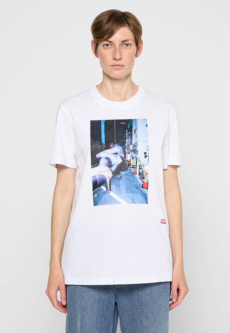 Weißes Baumwoll-T-Shirt mit einem Fotodruck auf der Vorderseite. Kurze Ärmel und lockere Passform. Strukturierter Stoff mit einem roten Akzent-Label im unteren linken Bereich.