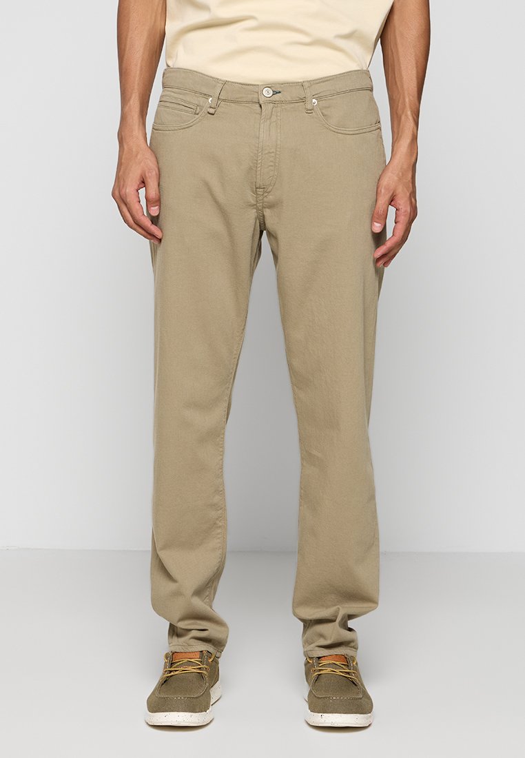 Beige Baumwollhosen im geraden Schnitt, ausgestattet mit fünf Taschen, einem Knopfverschluss und dezenten Steppnähten. Tragen Sie dazu grüne Sneakers.