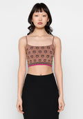 Braunes gestricktes Cropped-Top mit Spaghettiträgern, das ein Muster aus schwarzen lächelnden Gesichtern und einem pinken gerippten Saum aufweist. Darunter ein schwarzer enganliegender Rock.