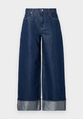 Dunkelblaue, weite Jeans mit hohem Bund, Fünf-Taschen-Design und umgekrempelten Säumen, die ein helleres Innenfutter zeigen.