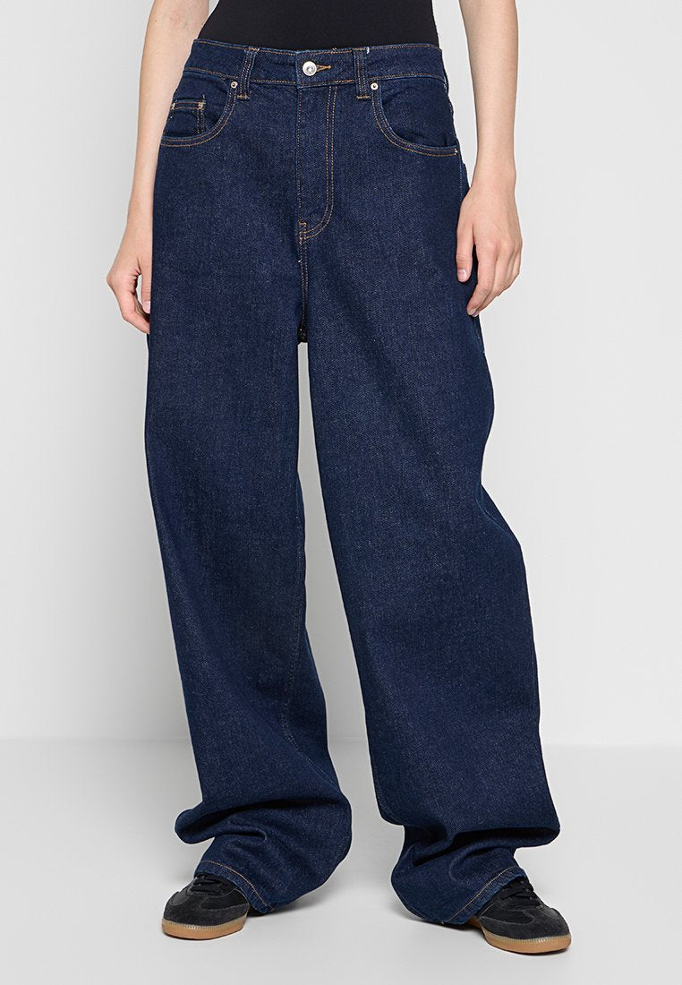 Weite Denim-Jeans in Dunkelblau mit kontrastierenden Nähten, ausgestattet mit Vordertaschen und einem Reißverschluss. Aus weichem, strapazierfähigem Stoff mit lockerer Passform.