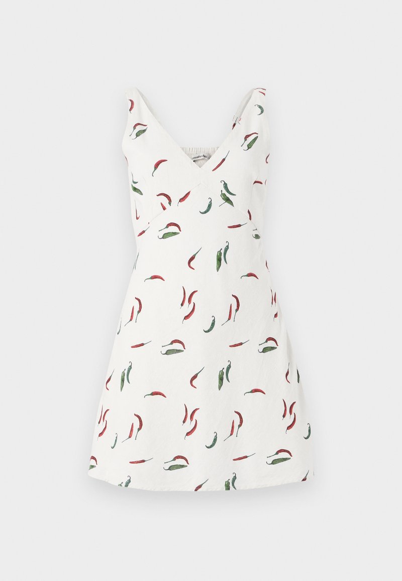 Weißes ärmelloses Kleid mit V-Ausschnitt, das mit einem Chili-Pfeffer-Muster in Rot und Grün verziert ist. Der Stoff wirkt leicht und geschmeidig.