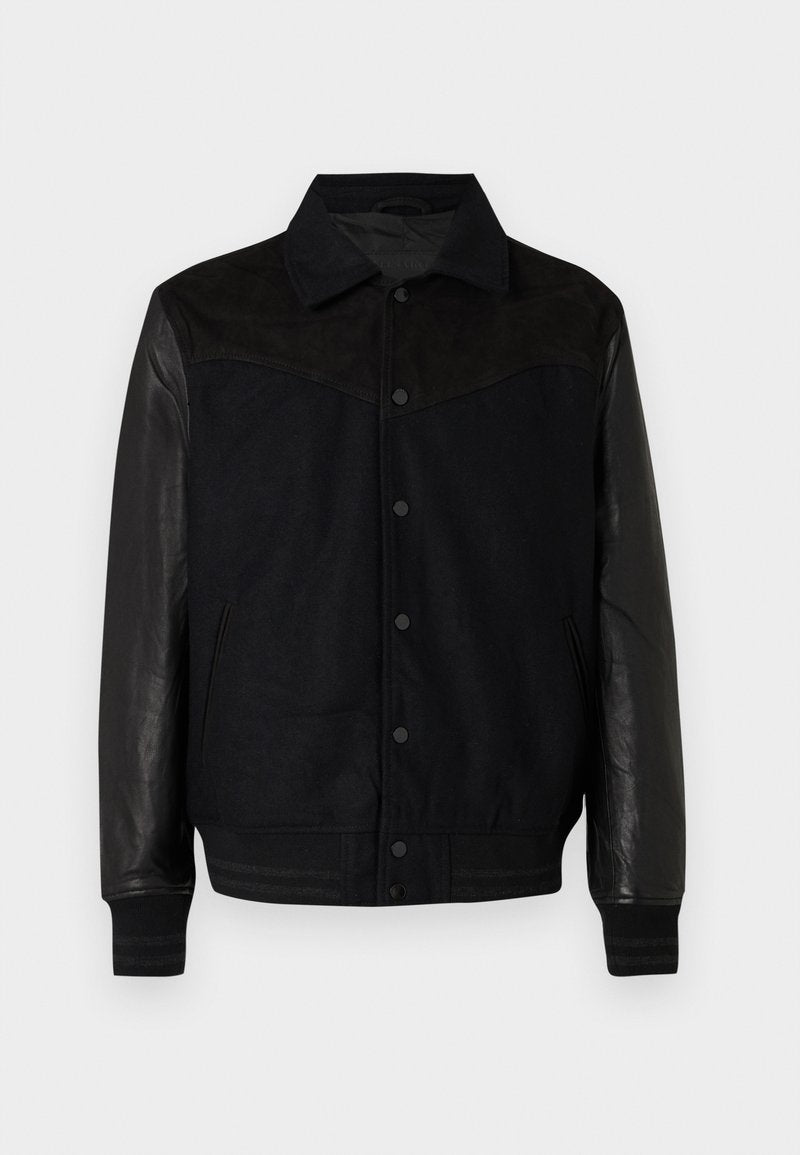 Schwarze Jacke mit Wollkörper und Lederärmeln. Mit einer durchgehenden Knopfleiste, seitlichen Taschen sowie gerippten Bündchen und Saum. Glatte Textur im gesamten Bereich.