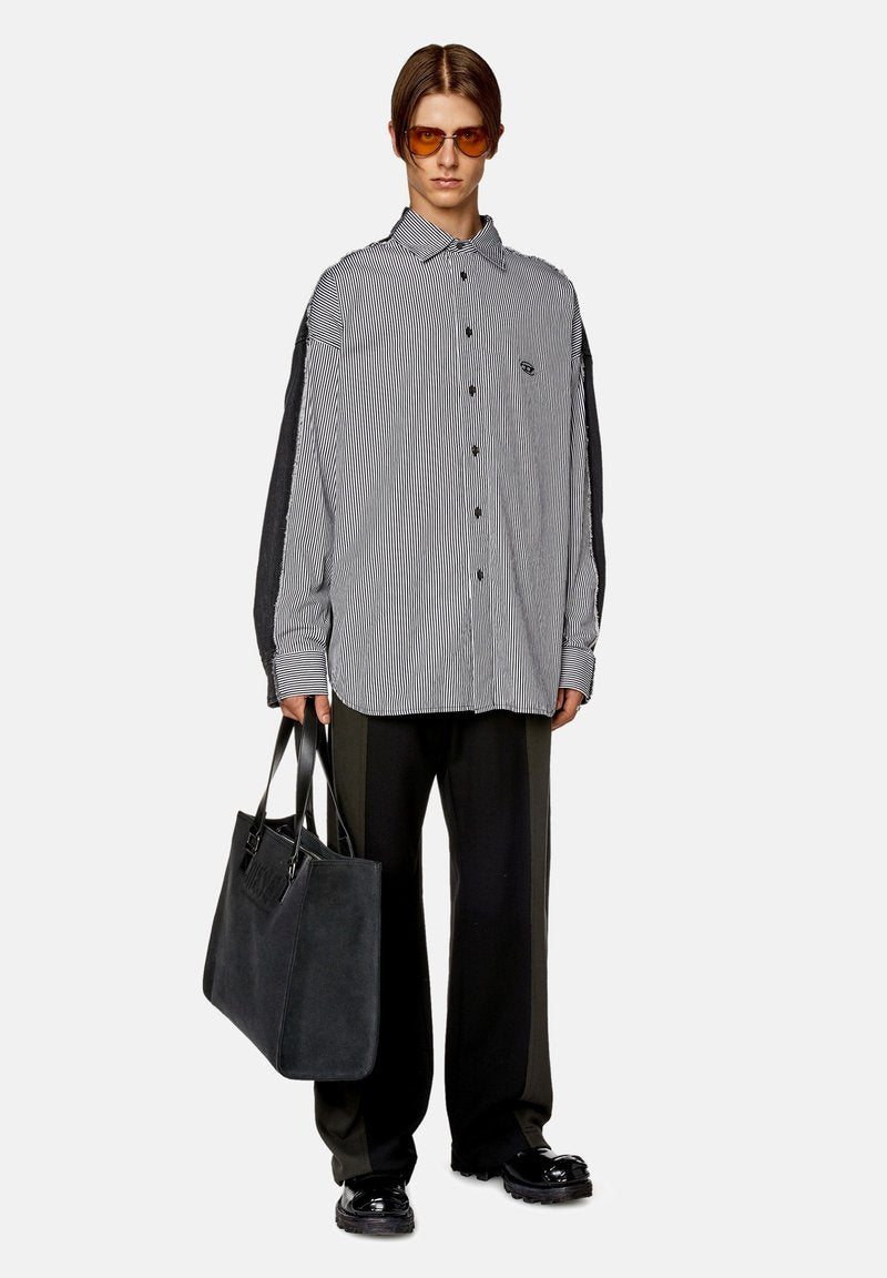 Gestreifte Button-Down-Bluse mit langen grauen Ärmeln, schwarze Hose und eine große schwarze Tragetasche. Das Model trägt braune Sonnenbrillen.