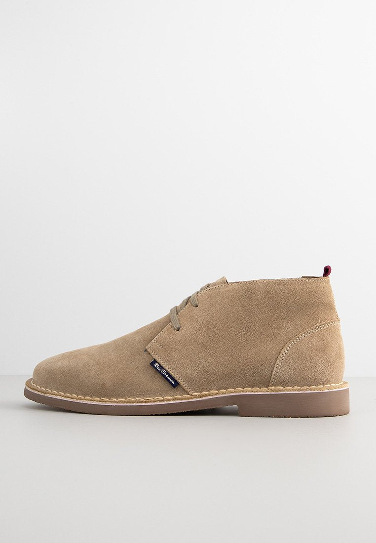 Beige Wildleder Stiefeletten mit runder Zehenpartie, Schnürverschluss, kontrastierender brauner Sohle und dekorativem Steppdetail.