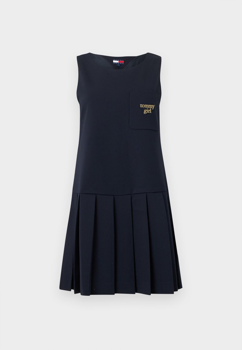 Marineblaues ärmelloses Kleid mit plissiertem Rock, mit einer aufgesetzten Tasche vorne, auf der "tommy girl" in goldener Stickerei zu lesen ist. Weiche Stoffstruktur.