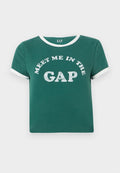 Grünes Baumwoll-T-Shirt mit weißen Akzenten am Kragen und an den Ärmeln. Auf der Vorderseite prangt in großen, glitzernden Buchstaben "MEET ME IN THE GAP".