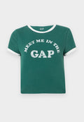 Grünes Baumwoll-T-Shirt mit weißen Akzenten am Kragen und an den Ärmeln. Auf der Vorderseite prangt in großen, glitzernden Buchstaben "MEET ME IN THE GAP".