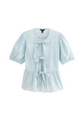 Himmelblaue Gingham-Bluse mit kurzen Puffärmeln, rundem Ausschnitt, drei vorderen Bindeschließen und Lochmuster-Details am Saum.