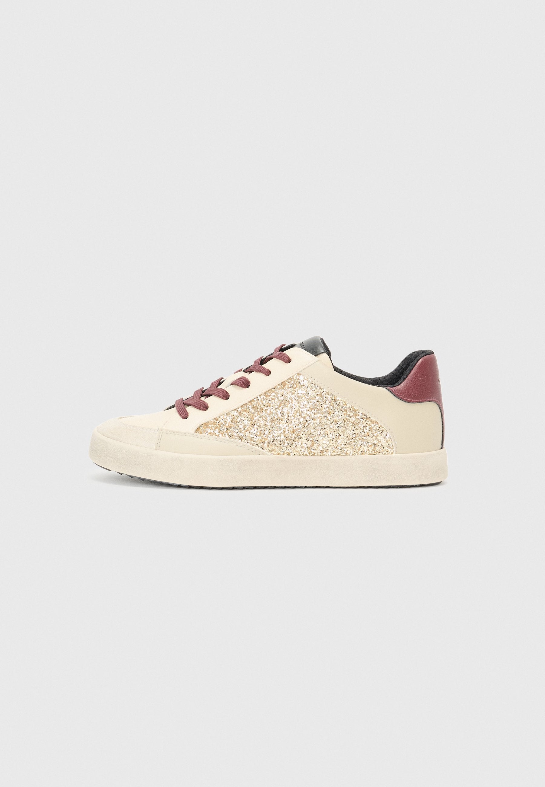 Sneaker mit einem oberen Teil aus cremefarbenem Leder, glitzerndem goldenen Seitenpanel, kastanienbraunen Akzenten und burgunderfarbenen Schnürsenkeln, ausgestattet mit einem strukturierten schwarzen Innenfutter.