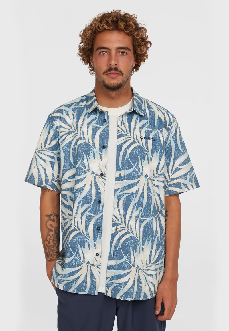 Kurzarmhemd mit einem blauen und weißen Blattmuster, Knopfleiste und lässiger Passform, kombiniert mit einem weißen T-Shirt darunter.