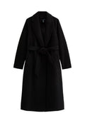 Schwarzer Trenchcoat mit Gürtel, langen Ärmeln, Reverskragen und Seitentaschen. Hergestellt aus einem strukturierten, weichen Stoff mit mittellangem Schnitt.