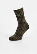 Gestrickte Socken in Dunkellila und Gold mit vertikalen Streifen, versehen mit dekorativen grünen und klaren Edelsteinen nahe dem oberen Rand.