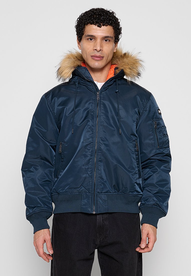 Marineblaue Bomberjacke mit pelzbesetzter Kapuze, orangefarbener Innenfütterung, Reißverschlusstaschen sowie gerippten Bündchen und Saum. Glattes, leichtes Gewebe.
