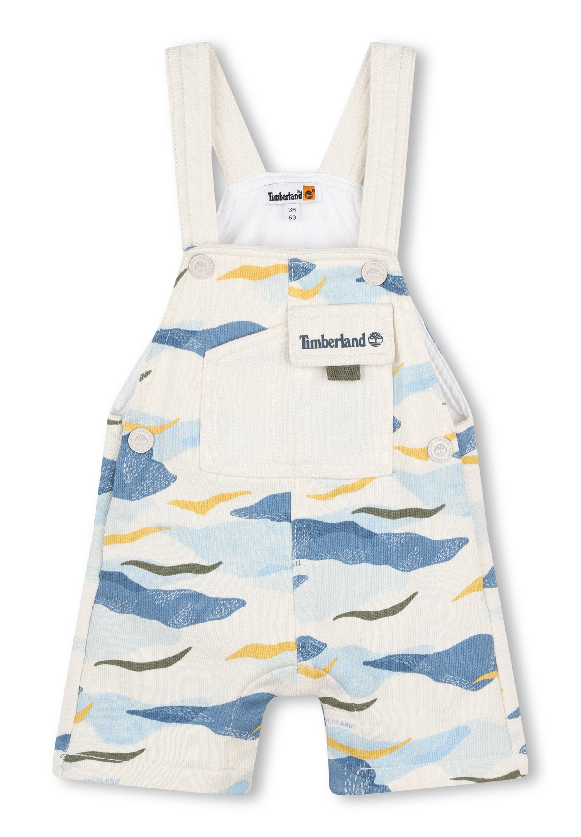 Weiße Overalls mit einem hellblauen, grünen und gelben Wellenmuster. Verfügt über verstellbare Träger, eine Fronttasche und ein Timberland-Logo-Patch.
