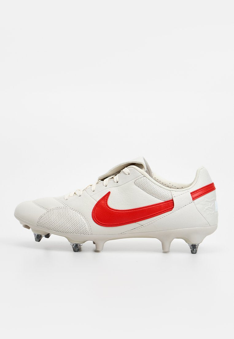 Weißer Fußballschuh mit rotem Nike-Swoosh, Schnürung vorne und sechs Metallstollen an der Sohle für besseren Halt auf Grasflächen.