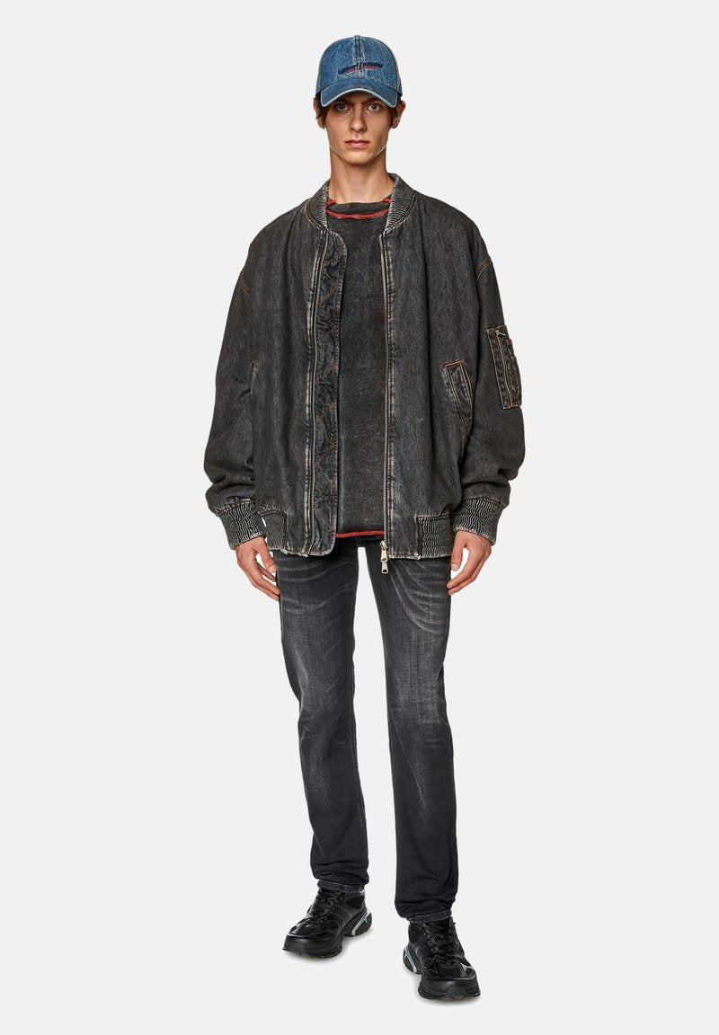 Schwarze Jeans-Bomberjacke mit gerippten Bündchen, kombiniert mit einem dunklen Langarmshirt, Jeans und einer hellblauen Jeansmütze. Schwarze Turnschuhe.