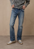 Hellblaue Jeans aus Denim mit geradem Bein, dezenten Verwaschungen und zwei Vordertaschen. Kombiniert mit silbernen Sneakers und einem grauen Pullover.