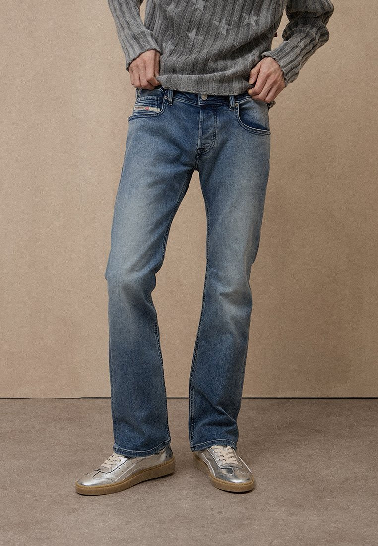 Hellblaue Jeans aus Denim mit geradem Bein, dezenten Verwaschungen und zwei Vordertaschen. Kombiniert mit silbernen Sneakers und einem grauen Pullover.
