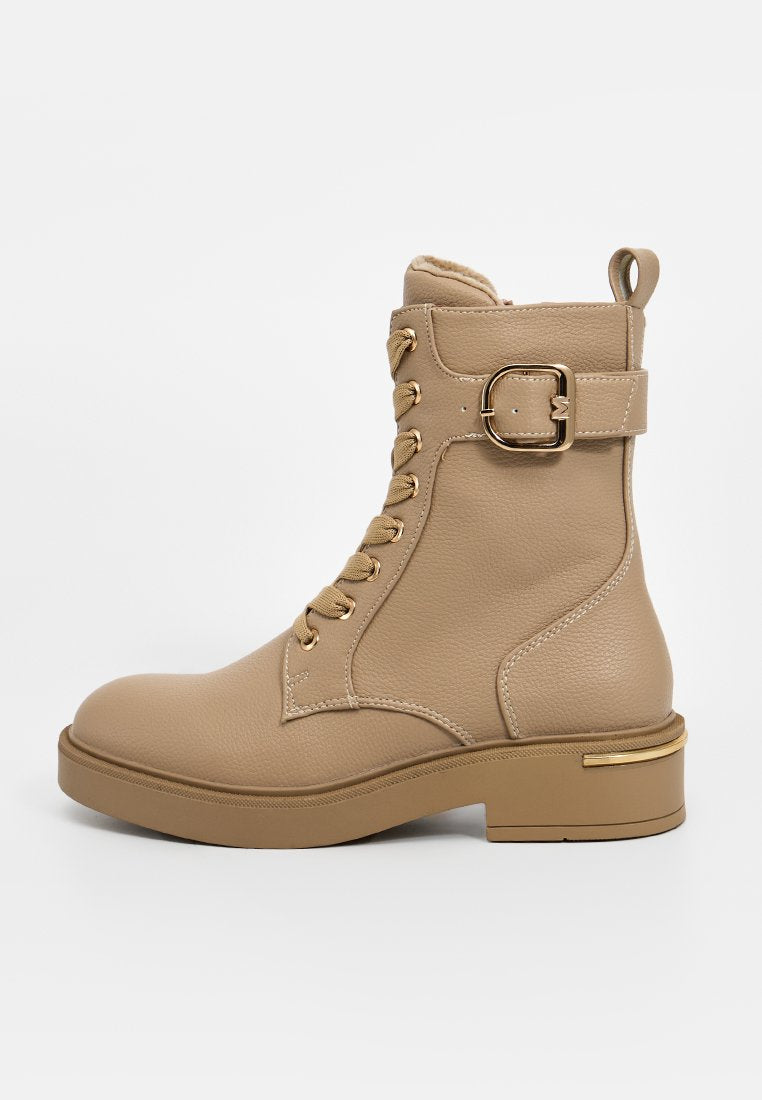Beige Lederstiefelette mit runder Zehenform, goldenen Hardware-Akzenten, Schnürung vorne und einem seitlichen Schnallen-Detail. Chunky Plateausohle.