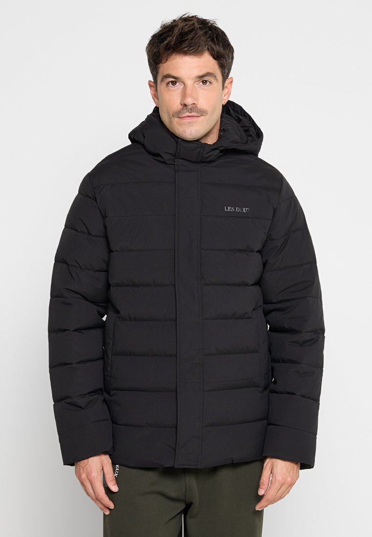 Schwarze Pufferjacke mit Kapuze, ausgestattet mit gesteppten Einsätzen, einem Reißverschluss vorne und einem dezenten Logo auf der Brust. Hergestellt aus leichtem, isoliertem Material.