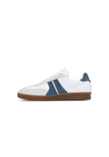 Weißer Ledersneaker mit marineblauen Wildlederakzenten, grauen Details und einer strukturierten braunen Gummisohle. Schnürdesign und abgerundete Zehenpartie.